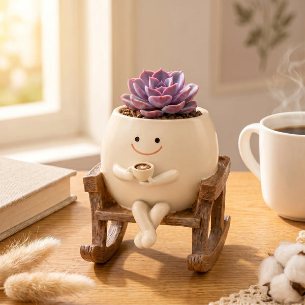 Decorative planter with a smiling face holding a cup, sitting on a small wooden bench on a table.